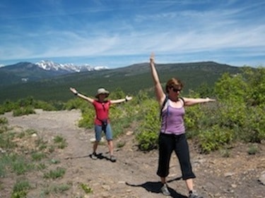 Two hikers arms raised on mountain overlook