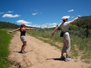 Two people stretching on a dirt trail